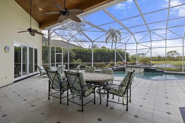 view of patio featuring ceiling fan, glass enclosure, and a pool with hot tub