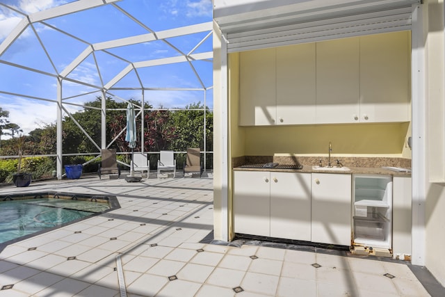 view of swimming pool featuring sink, a patio, and glass enclosure