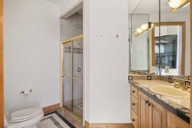 bathroom with vanity, a shower with door, and toilet