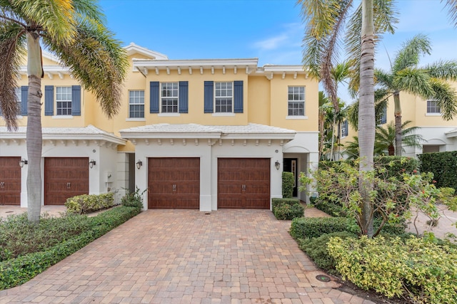 view of front of property featuring decorative driveway, an attached garage, and stucco siding