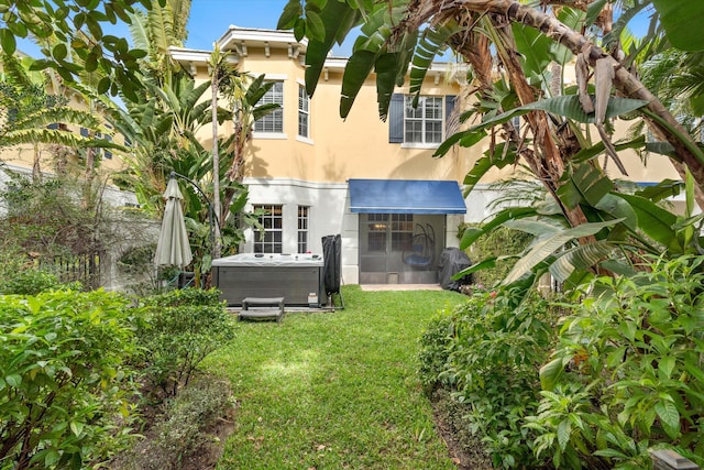 back of house with central AC, a hot tub, and a lawn