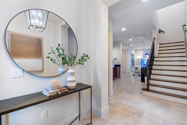 corridor with a notable chandelier, recessed lighting, baseboards, stairs, and ornamental molding