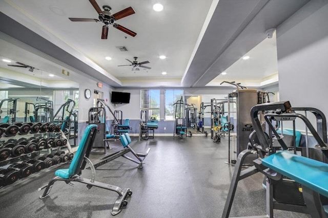 exercise room with ceiling fan and a tray ceiling