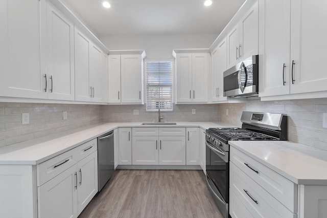 kitchen with stainless steel appliances, light hardwood / wood-style floors, white cabinets, and sink