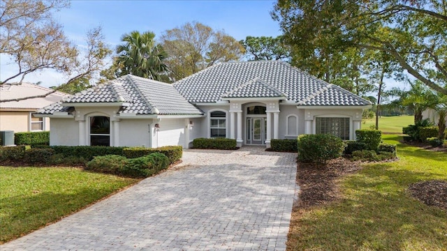 mediterranean / spanish-style home featuring a front yard, central air condition unit, and a garage