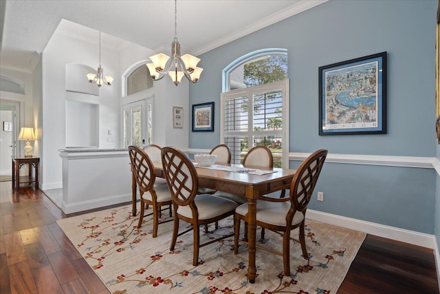 dining area with dark hardwood / wood-style floors, crown molding, french doors, and an inviting chandelier