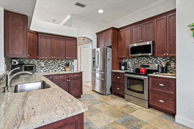 kitchen featuring decorative backsplash, sink, crown molding, light stone countertops, and appliances with stainless steel finishes