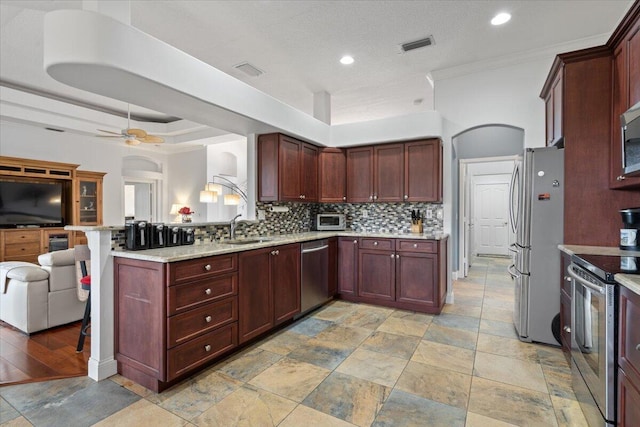 kitchen with ceiling fan, backsplash, kitchen peninsula, sink, and stainless steel appliances