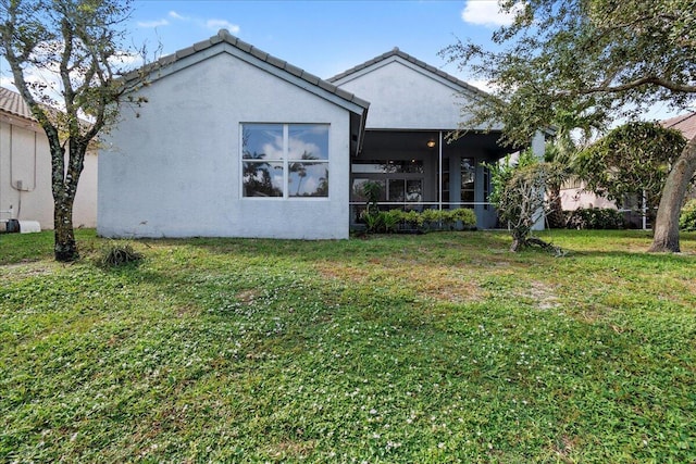 rear view of property featuring a yard and a sunroom