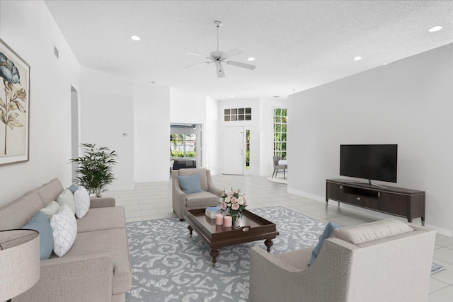 living room featuring a textured ceiling, ceiling fan, and light tile patterned floors