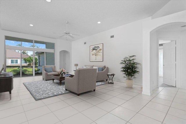 living room with a textured ceiling, ceiling fan, and light tile patterned floors