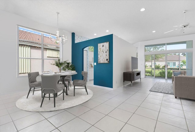 tiled dining space with ceiling fan with notable chandelier and a textured ceiling