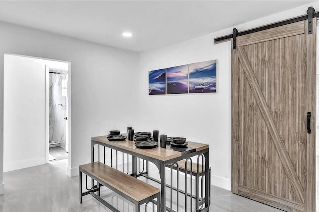 dining area with a barn door and concrete flooring