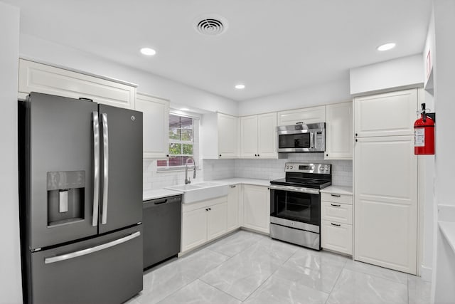 2112 N 14th Ter, Hollywood, FL 33020 - kitchen with stainless steel appliances, light countertops, white cabinets, tasteful backsplash, and light marble finish floors