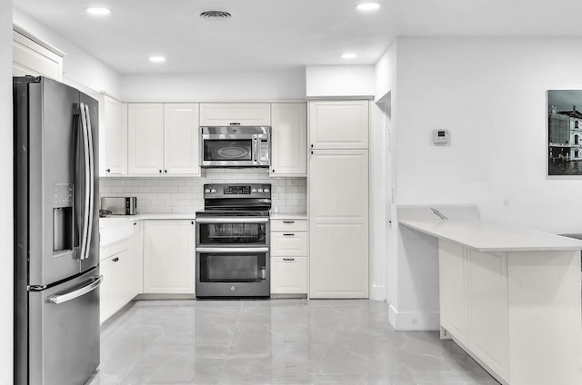 kitchen featuring kitchen peninsula, stainless steel appliances, white cabinetry, and tasteful backsplash