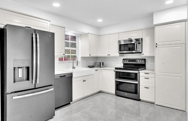 kitchen with stainless steel appliances, backsplash, white cabinetry, and sink