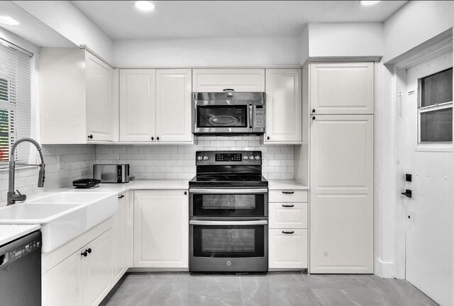 kitchen with white cabinetry, backsplash, range with two ovens, dishwasher, and sink