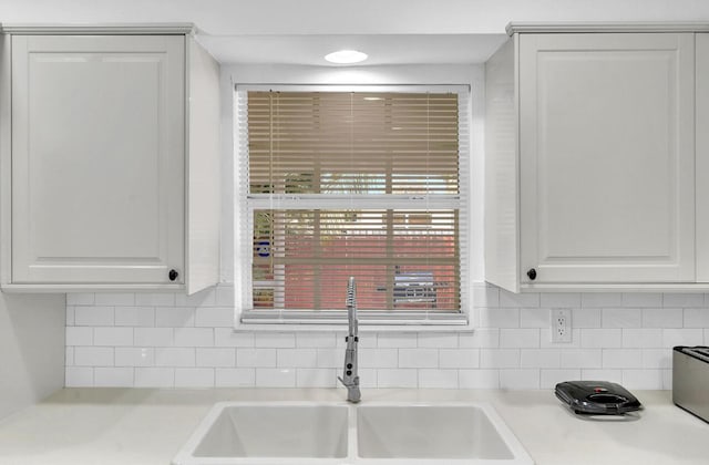 kitchen featuring white cabinetry, tasteful backsplash, and sink