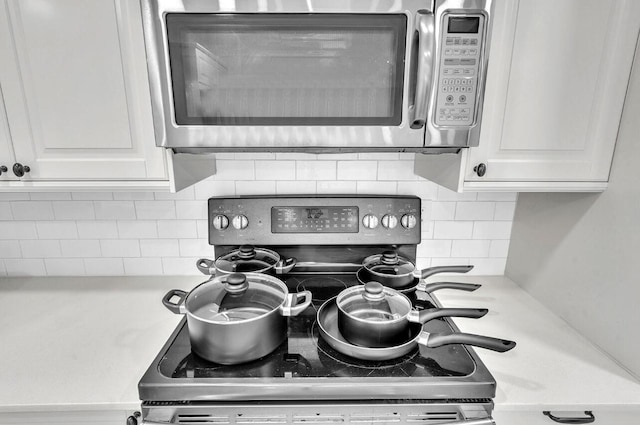 room details featuring white cabinets, appliances with stainless steel finishes, and tasteful backsplash