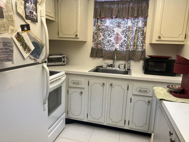 kitchen featuring white cabinets, a paneled ceiling, sink, and light tile patterned flooring