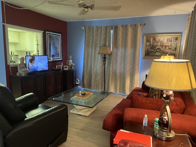 living room featuring ceiling fan, a textured ceiling, and light hardwood / wood-style flooring