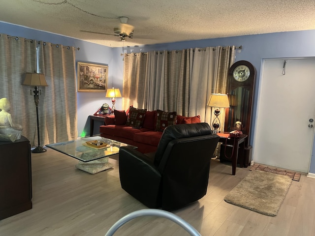 living room with hardwood / wood-style flooring, ceiling fan, and a textured ceiling