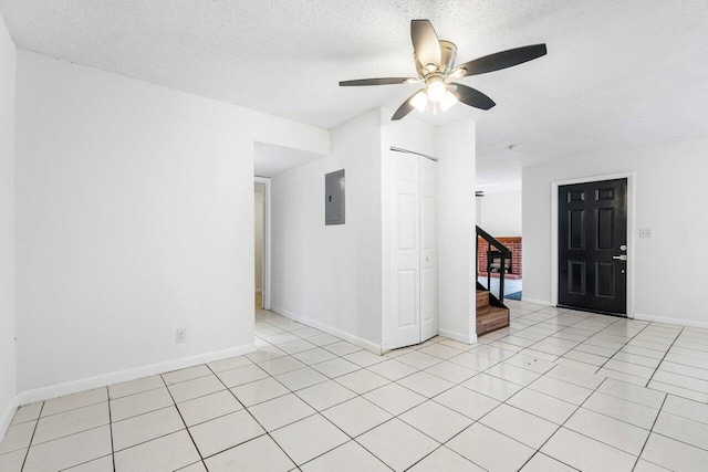 tiled empty room with ceiling fan, a textured ceiling, and electric panel