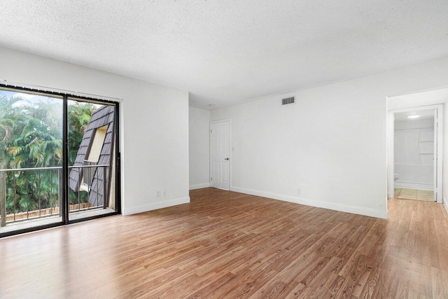 spare room featuring a textured ceiling and light hardwood / wood-style floors