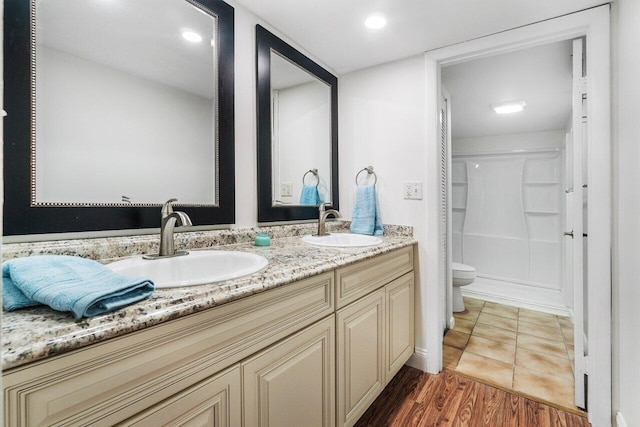 bathroom featuring toilet, a shower, hardwood / wood-style floors, and vanity