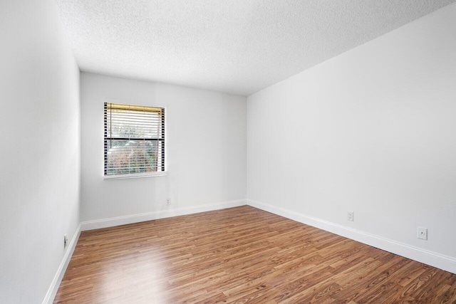 empty room featuring a textured ceiling and hardwood / wood-style floors