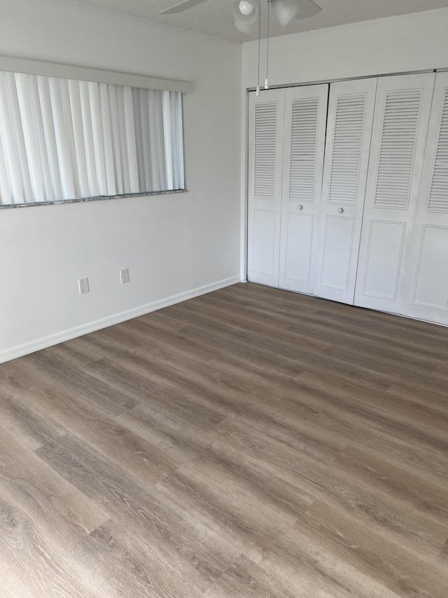 unfurnished bedroom featuring dark wood-type flooring, ceiling fan, and a closet