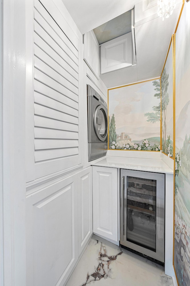 bar with white cabinets, stacked washer and dryer, and beverage cooler