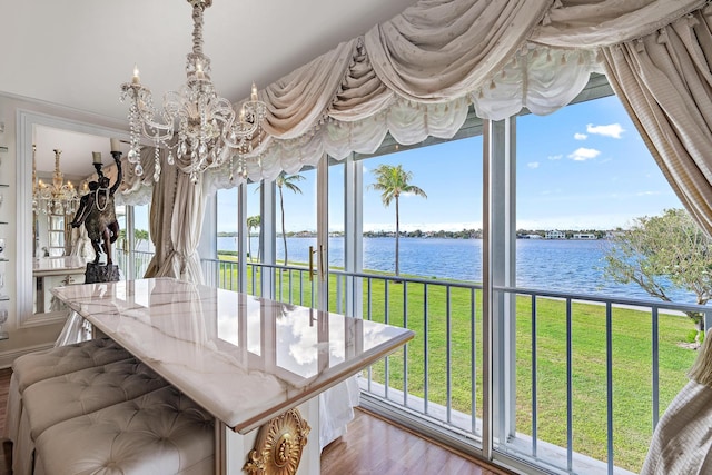 sunroom / solarium with a water view and a chandelier