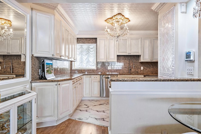 kitchen featuring sink, crown molding, dishwasher, a notable chandelier, and white cabinets