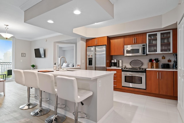 kitchen featuring an island with sink, a breakfast bar area, appliances with stainless steel finishes, light tile patterned flooring, and ornamental molding