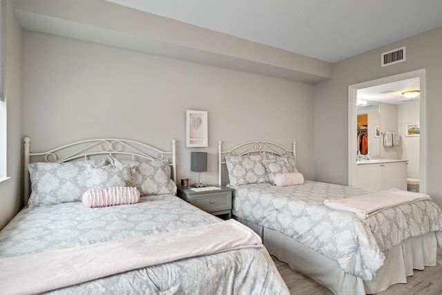 bedroom featuring ensuite bathroom and light hardwood / wood-style flooring