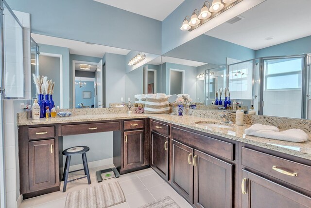 bathroom featuring a shower with shower door, vanity, and tile patterned floors