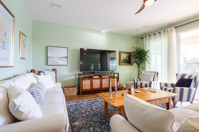 living room with ceiling fan, wood-type flooring, and a textured ceiling