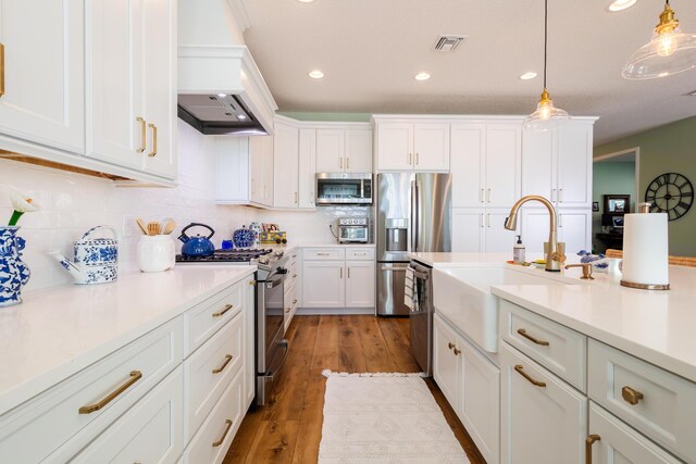 kitchen featuring pendant lighting, decorative backsplash, hardwood / wood-style flooring, appliances with stainless steel finishes, and white cabinets