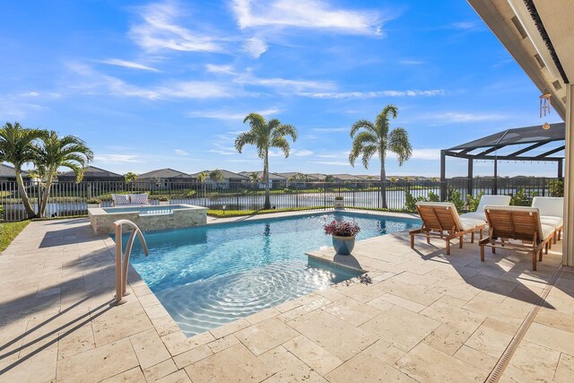 view of pool featuring a patio area, glass enclosure, a water view, and an in ground hot tub