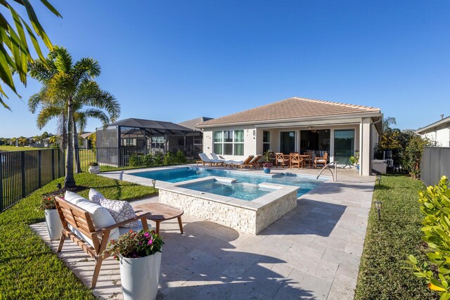 view of pool with an in ground hot tub, a patio area, and glass enclosure