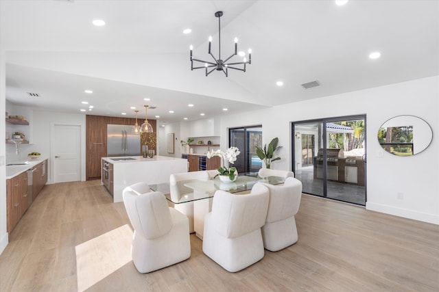 dining room with light hardwood / wood-style floors, sink, an inviting chandelier, and vaulted ceiling