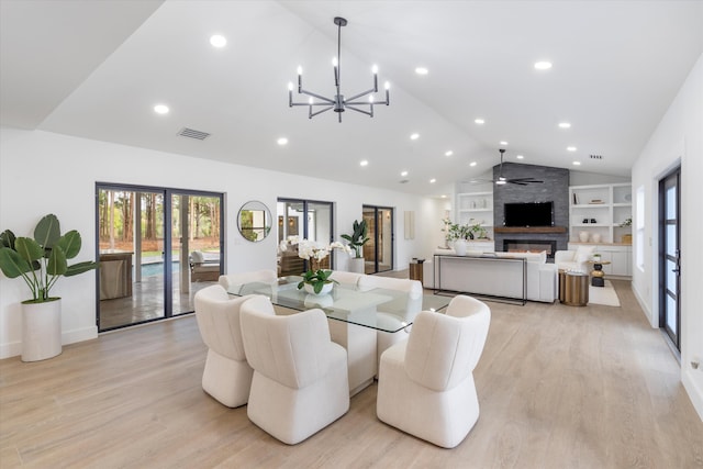 dining area featuring ceiling fan with notable chandelier, lofted ceiling, a large fireplace, built in features, and light hardwood / wood-style flooring