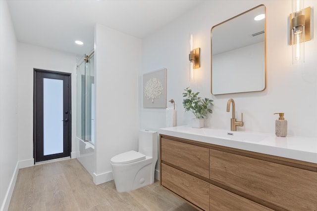 full bathroom featuring toilet, enclosed tub / shower combo, vanity, and hardwood / wood-style floors