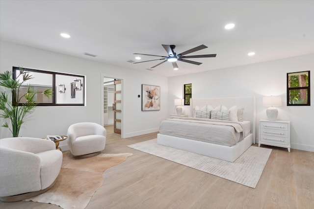 bedroom featuring ceiling fan, a walk in closet, a closet, and light hardwood / wood-style floors