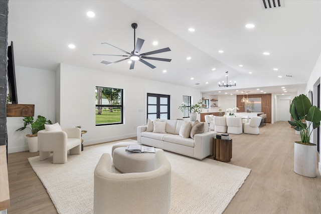 living room featuring ceiling fan with notable chandelier, lofted ceiling, and light wood-type flooring