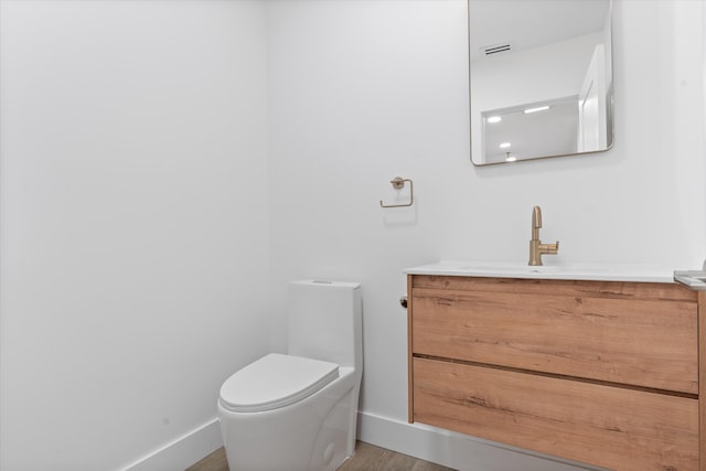 bathroom with hardwood / wood-style floors, toilet, and vanity