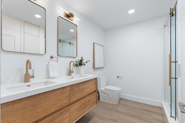 bathroom with toilet, a shower with door, hardwood / wood-style flooring, and vanity