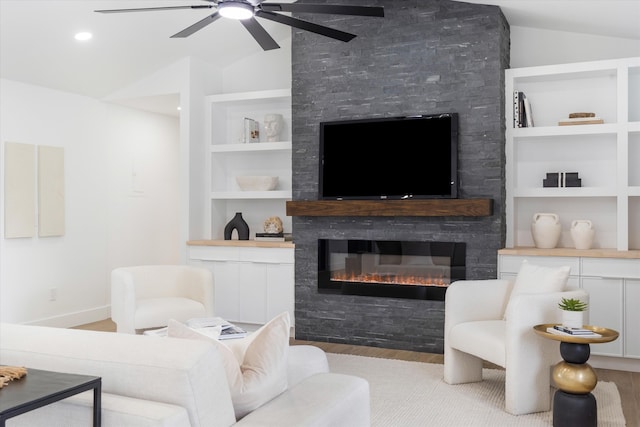 living room featuring light wood-type flooring, built in shelves, vaulted ceiling, and a fireplace