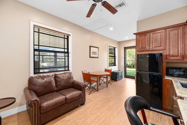 interior space with light stone counters, ceiling fan, light hardwood / wood-style floors, and black appliances